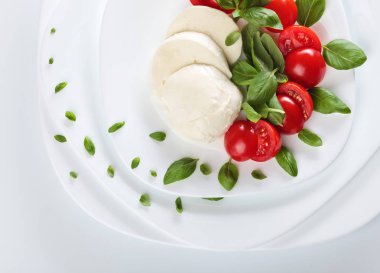 Beyaz tabakta domates ve yeşil Fesleğenli Mozzarella peyniri. Sağlıklı organik gıda.