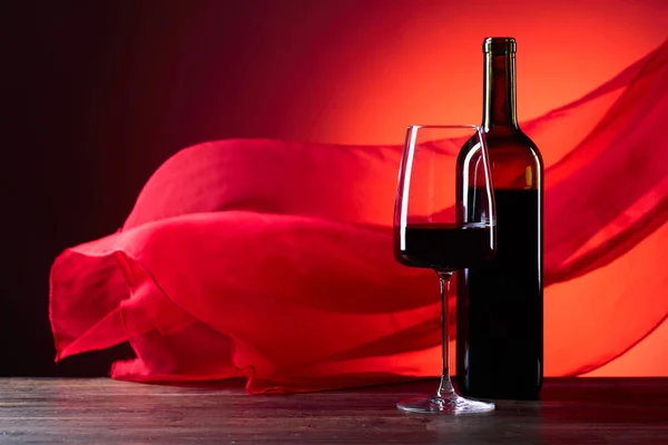 眼镜和瓶的忠告葡萄酒在红色的背景 红色的纯粹的布料在风中飘扬 复制空间 — 图库照片