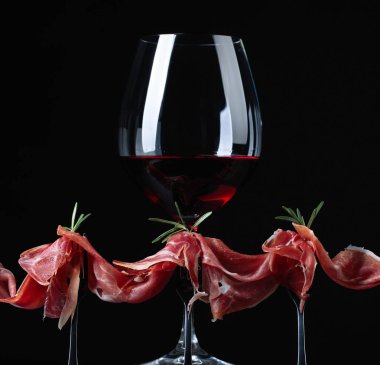 Prosciutto biberiye ve siyah bir zemin üzerine kırmızı şarap ile. Metniniz için kopya alanı.