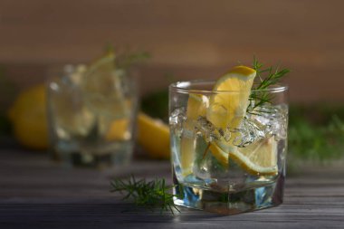 Cin, tonik ve limon dilimleri eski ahşap bir masa. Alkollü kokteyl limon dilimleri ve ardıç şube ile.