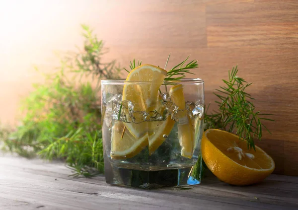 Cin, tonik ve limon dilimleri eski ahşap bir masa. Alkollü kokteyl limon dilimleri ve ardıç şube ile.