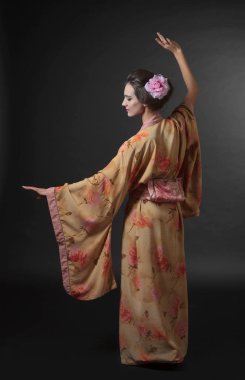 Geleneksel Japon kimono siyah bir arka plan üzerinde dans eden kadın. Mükemmel saç ve makyaj ile genç güzel kadın.