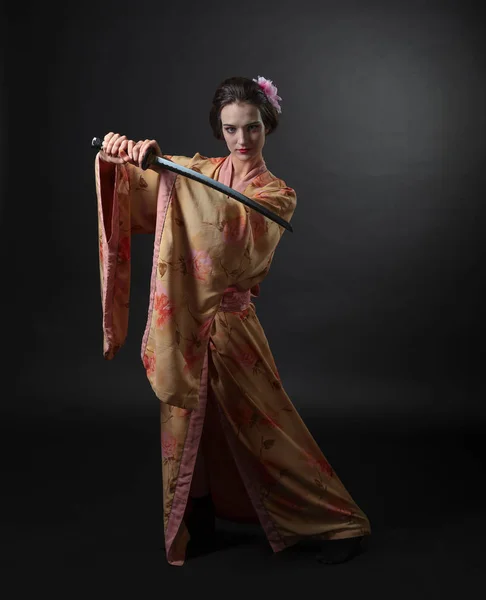 美丽的女人在传统的日本和服与武士刀在黑色背景 完美的头发和化妆的年轻美丽的女人 — 图库照片