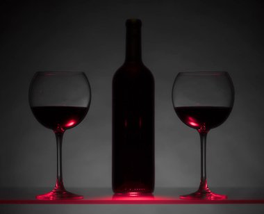 Gözlük ve karanlık bir arka plan üzerinde kırmızı şarap şişe.