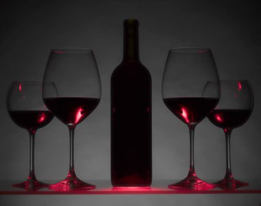 Gözlük ve karanlık bir arka plan üzerinde kırmızı şarap şişe.