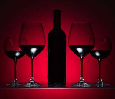 Gözlük ve kırmızı bir arka plan üzerinde kırmızı şarap şişe.