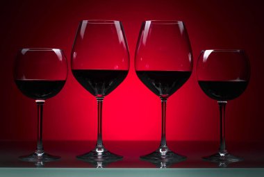 Kırmızı bir arka plan üzerinde kırmızı şarap gözlük.