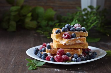  Ahududu ve eski ahşap bir masa üzerinde yaban mersini ile lezzetli tatlı waffle .