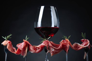 Prosciutto biberiye ve karanlık bir arka plan üzerinde kırmızı şarap ile. Metniniz için kopya alanı.