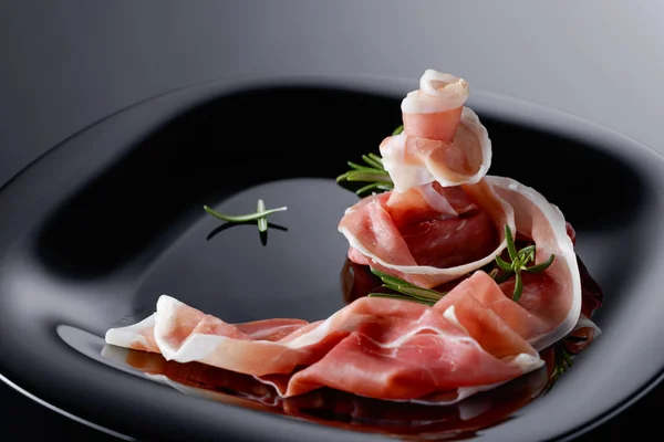 Prosciutto Mit Rosmarin Auf Schwarzem Teller — Stockfoto