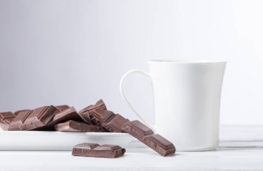 Beyaz kupa sıcak içecek ve bitter çikolata parçaları. Metniniz için kopya alanı.