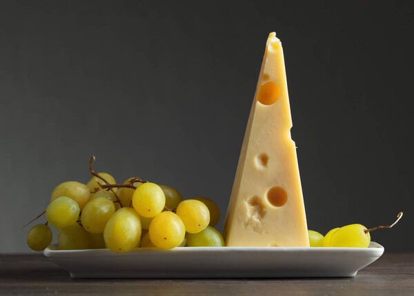 Cheese with grapes on a old wooden table.