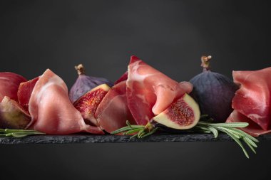 Prosciutto incir ve biberiye siyah bir arka plan ile.