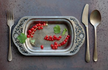 Redcurrants metal çanak çatal ve bıçak üzerinde. Sağlıklı beslenme, diyet ve antioksidan için kavram. Üstten görünüm.