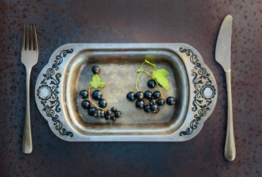Blackcurrants metal çanak çatal ve bıçak üzerinde. Sağlıklı beslenme, diyet ve antioksidan için kavram.