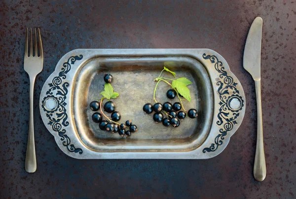 Blackcurrants metal çanak çatal ve bıçak üzerinde. Sağlıklı beslenme, diyet ve antioksidan için kavram.