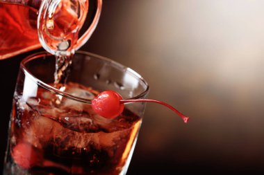 Viski bir sürahi buzlu cam içine dökülür. Kokteyl Manhattan kiraz ile. Kopya alanı.