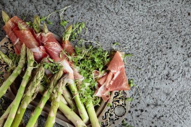 Prosciutto ile tere salatası metal bir arka plan üzerinde sarılı kuşkonmaz. Üstten görünüm, metniniz için kopya alanı. 