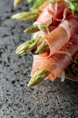 Prosciutto ile tere salatası gri metal arka plan üzerinde sarılı kuşkonmaz.