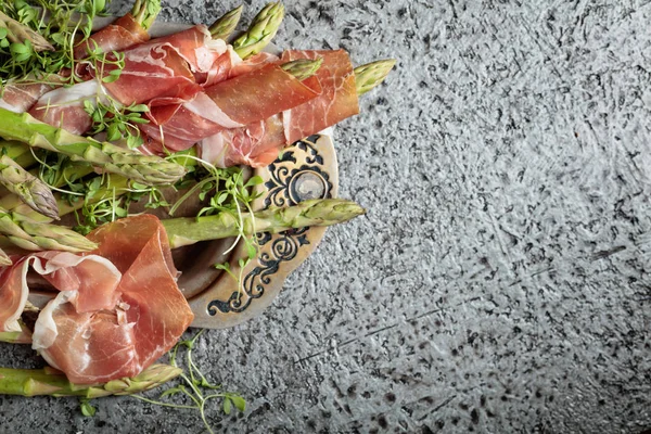 Prosciutto ile tere salatası metal bir arka plan üzerinde sarılı kuşkonmaz. Üstten görünüm, metniniz için kopya alanı. 