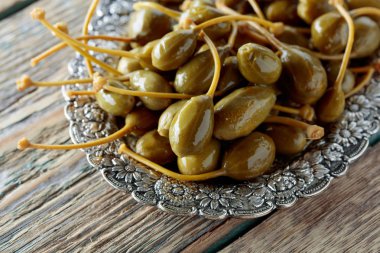 Metal tabak içinde turşu Kapari Karpuzu. Capparis yenilebilir meyve. Çilek garnitür olarak kullanılır. Eski ahşap arka plan.