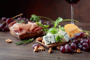 Çeşitli peynirler, üzüm ve prosciutto eski bir ahşap tablo.