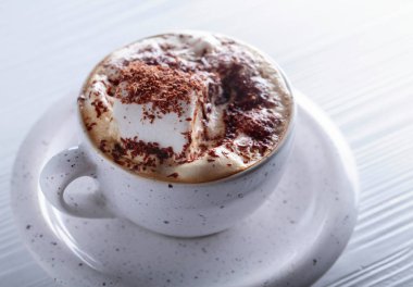 Sıcak çikolata ve üzerine çikolata parçacıkları serpiştirilmiş beyaz ahşap masa..