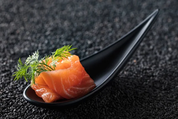 Siyah susam arka plan üzerine dereotu ile tuzlanmış somon dilim.