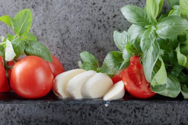 Mozzarella fesleğen ve bir arka plan üzerinde domates ile eski duvar gri. Metniniz için kopya alanı.