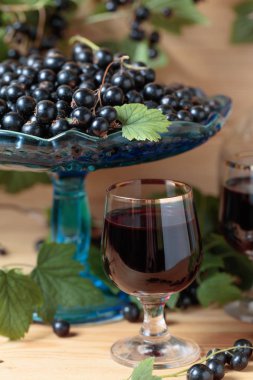 Ev yapımı siyah frenk üzümü likör ve dal, ahşap arka plan taze çilek.