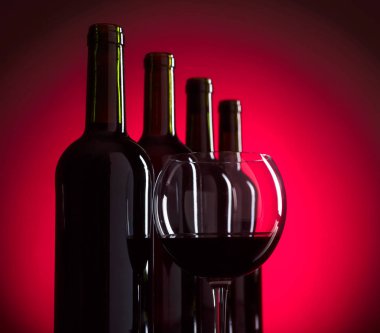 Gözlük ve kırmızı arka plan, metniniz için kopya alanı üzerinde kırmızı şarap şişeleri.