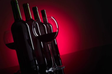 Gözlük ve kırmızı arka plan, metniniz için kopya alanı üzerinde kırmızı şarap şişeleri.