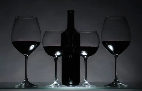 Gözlük Karanlık Bir Arka Plan Üzerinde Kırmızı Şarap Şişe — Stok fotoğraf