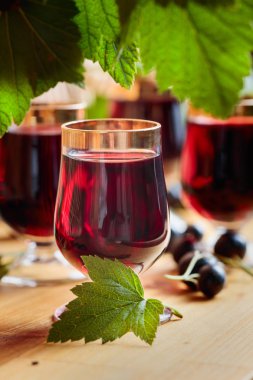 Ev yapımı siyah frenk üzümü likör ve taze meyveler, ahşap arka plan.