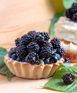 Lezzetli böğürtlen kek çilek ve krema ahşap bir masa üzerinde ile.