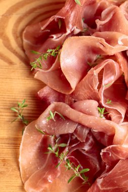 İtalyan prosciutto crudo veya jamon ahşap bir masa üzerine kekik ile. Üstten görünüm.