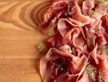 İtalyan prosciutto crudo veya jamon ahşap bir masa üzerine kekik ile. Üstten görünüm, metniniz için kopya alanı.