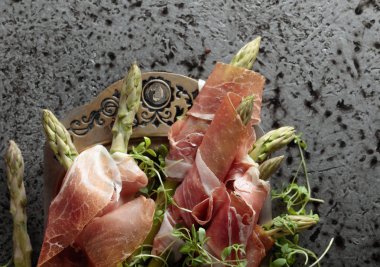 Prosciutto ile tere salatası metal bir arka plan üzerinde sarılı kuşkonmaz. Üstten görünüm, metniniz için kopya alanı. 