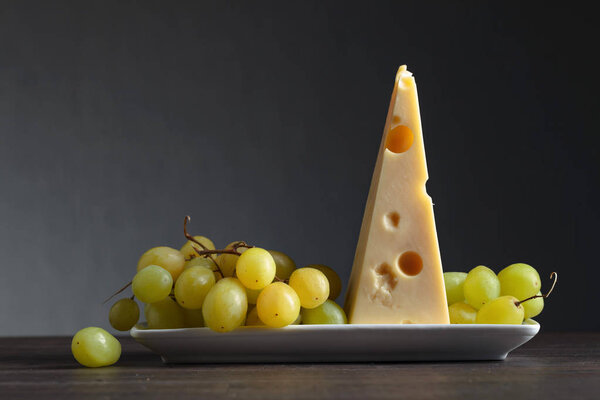 Cheese with grape on a old wooden table