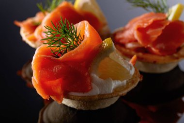 Somon balığı, krema ve bir dilim limon siyah bir arka plan ile tartlets.