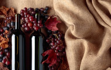 Çuval bezi, üstten görünüm üzerinde asma yaprağı kadar kırmızı şarap şişeleri ve taze üzüm ile kurutulmuş. 