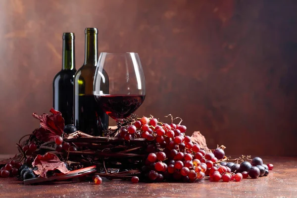 Red wine and fresh grapes with dried up vine leaves, copy space for your text.