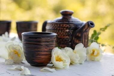Seramik bardak, Çaydanlık ve beyaz köpek gül bahçesinde eski ahşap bir masa üzerinde. Yabani gül ile aromatik ve canlandırıcı çay.