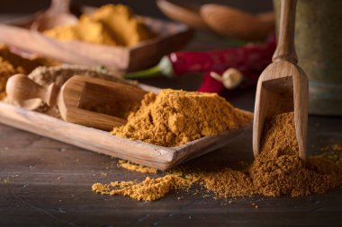 Eski ahşap bir masa üzerinde tahta kaşıklar ile çeşitli Hint baharat.