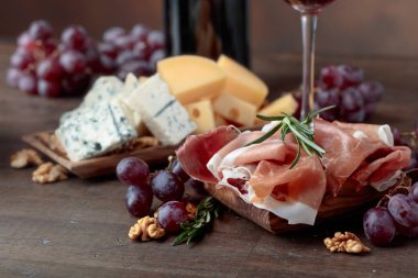 Prosciutto çeşitli peynirler, üzüm ve eski ahşap bir masa üzerinde ceviz.