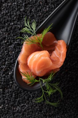 Tuzlanmış somon siyah susam arka plan üzerine dereotu ile dilim. Üstten Görünüm.