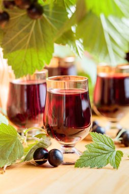 Ev yapımı siyah frenk üzümü likör ve taze meyveler, ahşap arka plan.