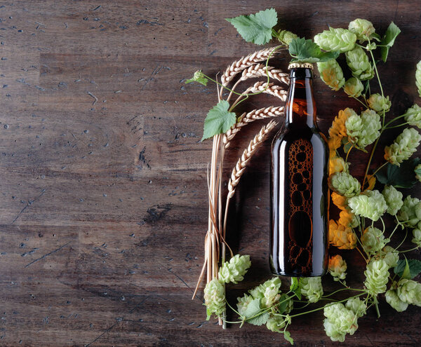 Бутылка пива, зерна и хмеля на старом деревянном фоне. Вид сверху. Свободное место для текста
.