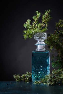 Mavi cin crystal sürahi ve ardıç daldaki meyveleri siyah bir arka plan ile. Metniniz için kopya alanı.