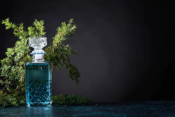 Mavi cin crystal sürahi ve ardıç daldaki meyveleri siyah bir arka plan ile. Metniniz için kopya alanı.